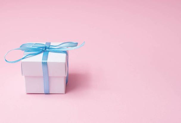 white gift box with blue ribbon on pink background with copy space - Photo, Image