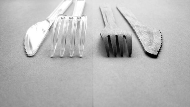 Contrast plastic and bamboo wooden fork and knife black and white. Eco-friendly disposable cutlery - Photo, Image