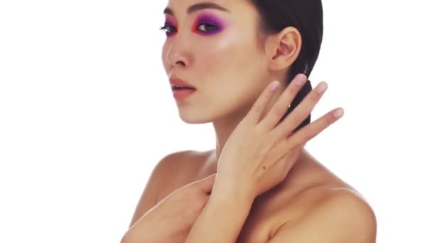 Een mooie jonge halfnaakte vrouw met heldere mode oog make-up is het aanraken van haar haar geïsoleerd over witte achtergrond - Video