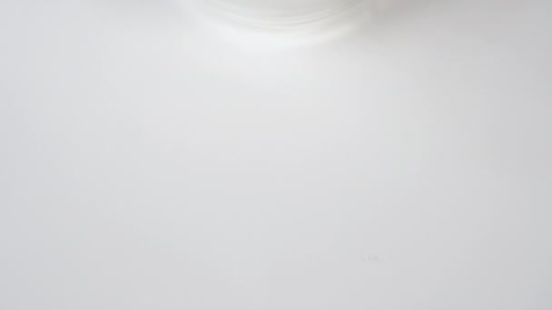 Valkoiset lääkekapselit lasipullossa lähikuva valkoisella pöydällä. Makroruiske. Hidastettu kamera. Näkymä ylhäältä. Koronavirushoito. Covid-19-rokotteiden käyttö
 - Materiaali, video