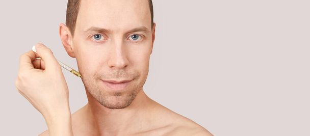 Man skin care routine. Oil pipette near male face - Fotoğraf, Görsel