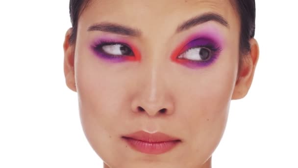 A close-up view of an attractive young half-naked woman with bright fashion eye makeup is looking aside isolated over white background - Záběry, video