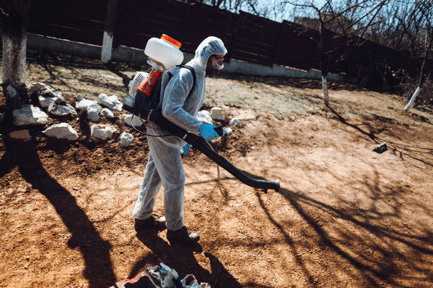 Retrato de homem, trabalhador agrícola vestindo roupas protetoras e pulverizando pesticida industrial
 - Foto, Imagem