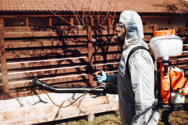 Trabalhador industrial e agricultor usando máquina, misturador de pesticidas e inseticida pulverização e vestindo roupas de proteção
  - Foto, Imagem