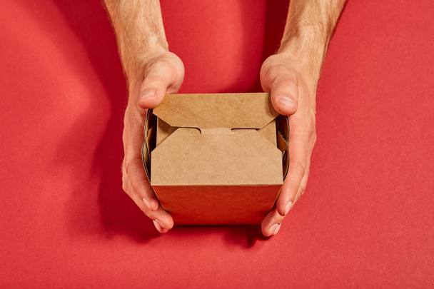 top view of man holding carton takeaway box on red - Foto, immagini