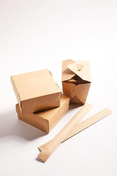 cajas de cartón con comida china y palillos en el embalaje en blanco
  - Foto, Imagen
