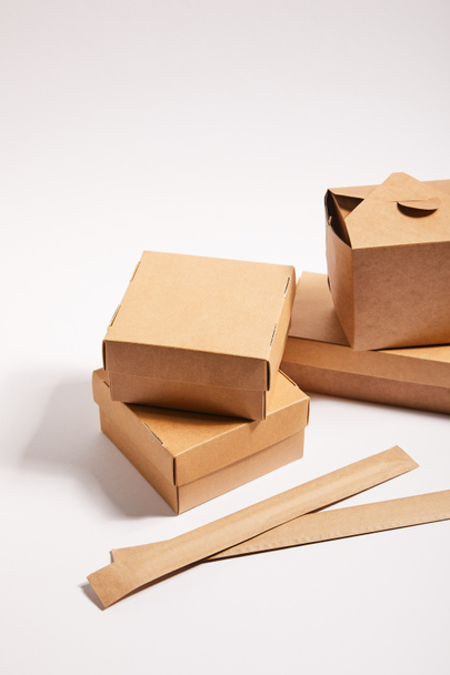 palillos en el embalaje de papel cerca de cajas de cartón con comida china en blanco
  - Foto, Imagen