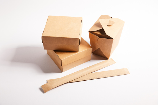 palillos en el embalaje de papel cerca de cajas de comida para llevar con comida china en blanco
  - Foto, Imagen