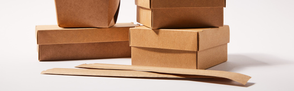 imagen horizontal de palillos en el embalaje de papel cerca de cajas de comida para llevar con comida china en blanco
  - Foto, Imagen