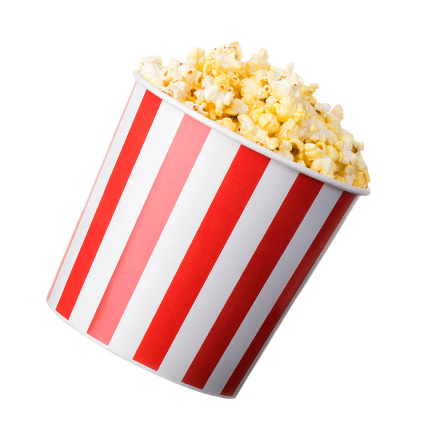 Paper striped bucket with popcorn isolated on white background with clipping path. Concept of cinema or watching TV. - Foto, Imagen
