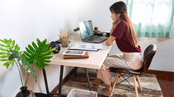 Привлекательная молодая красивая азиатская женщина Предприниматель или фрилансер, работающий дома с ноутбуками бизнес-отчеты и онлайн-коммуникации на диване гостиной, работающий дистанционно - Фото, изображение