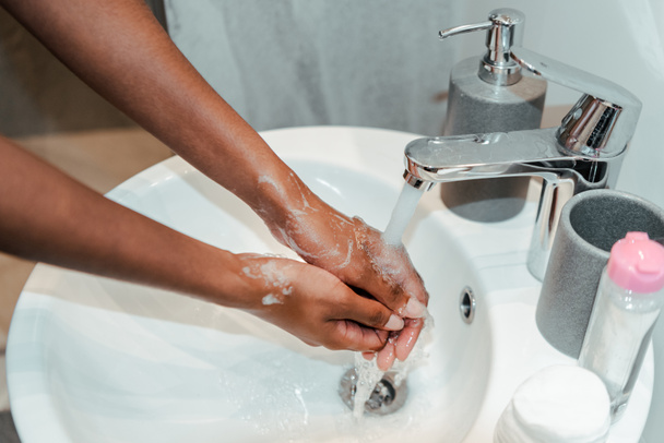 Обрезанный вид африканской женщины, моющей руки в ванной - Фото, изображение
