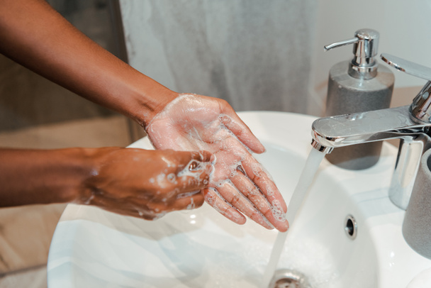 バスルームで石鹸で手を洗うアフリカ系アメリカ人女性の作物ビュー - 写真・画像