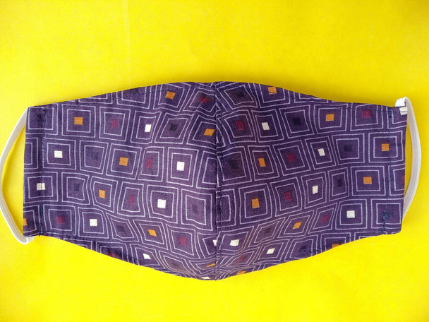 Фиолетовая многоразовая защитная маска для лица ручной работы. Маска ручной работы из текстиля, защищает от пыли и вирусов. время карантина, концепция защиты от вирусов - Фото, изображение