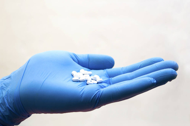 La main dans un gant médical prend une pilule sur la table - choix du médicament, coronavirus, covid19
 - Photo, image