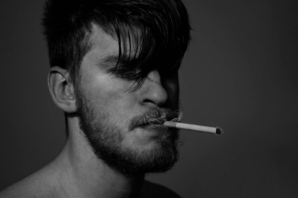 Homme blanc à la barbe et aux cheveux longs, cigarette fumante en noir et blanc
 - Photo, image
