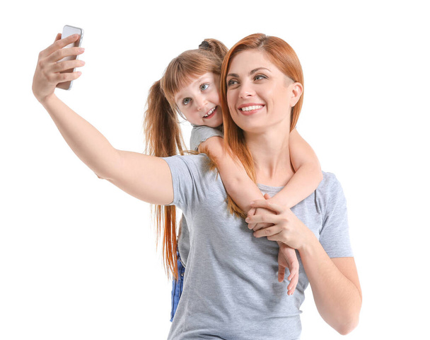 Woman and her little daughter taking selfie on white background - Photo, Image