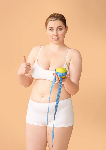 Избыточный вес женщины с яблоком и измерительной лентой на цветном фоне. Концепция потери веса
 - Фото, изображение
