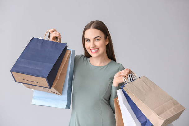 Mujer joven con bolsas de compras sobre fondo gris
 - Foto, Imagen