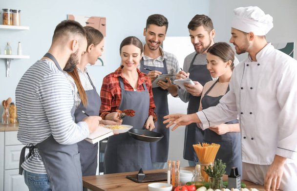 Αρσενικό σεφ και ομάδα νέων κατά τη διάρκεια των μαθημάτων μαγειρικής - Φωτογραφία, εικόνα