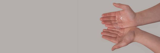 Hands of a young male with liquid soap in the palms on a grey background. Hand washing. Minimal hygiene, virus protection concept - Foto, imagen