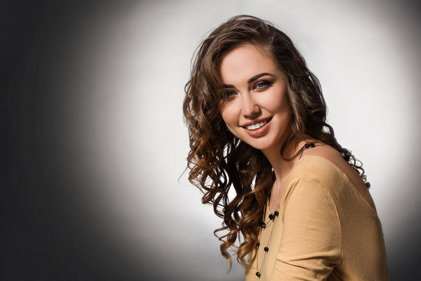 Beautiful young woman with curly hair on dark background - Фото, зображення