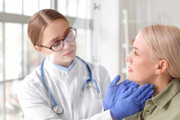 Médico examinando mulher sênior com problema da glândula tireóide na clínica
 - Foto, Imagem