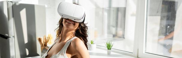 Positive girl using vr headset in kitchen, panoramic shot  - Photo, Image