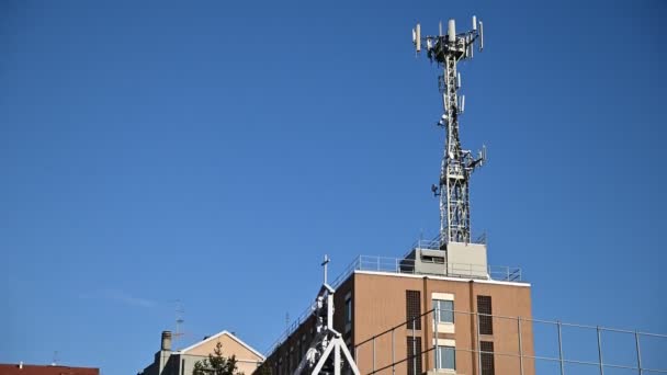 Aufnahmen einer Mobilfunkantenne auf dem Dach eines Gebäudes. Sonniger Tag, vertikale Bewegung. - Filmmaterial, Video