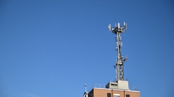 Kuvaa matkapuhelinverkon antennista rakennuksen katolla. Aurinkoinen päivä, pystysuora liike
. - Materiaali, video