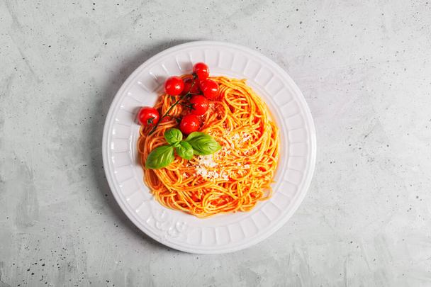 Pasta with tomato sauce and cherry tomatoes with basil on a white background. Copy space. Fresh or dry spaghetti is cooked in a large pot with salted boiling water, and then dried in a colander - Photo, image