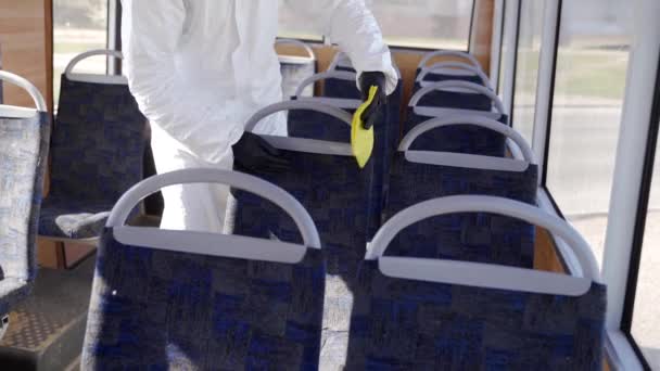 Hazmat team worker disinfects bus interior with antibacterial sanitizer wipes on coronavirus covid-19 quarantine. Man in gas mask, hazmat suit cleans public transport seats, handholds with rag. - Πλάνα, βίντεο