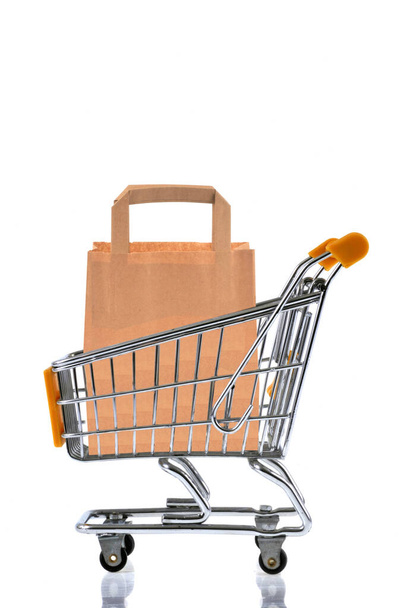 Paper bag in supermarket cart on white background  - Photo, Image