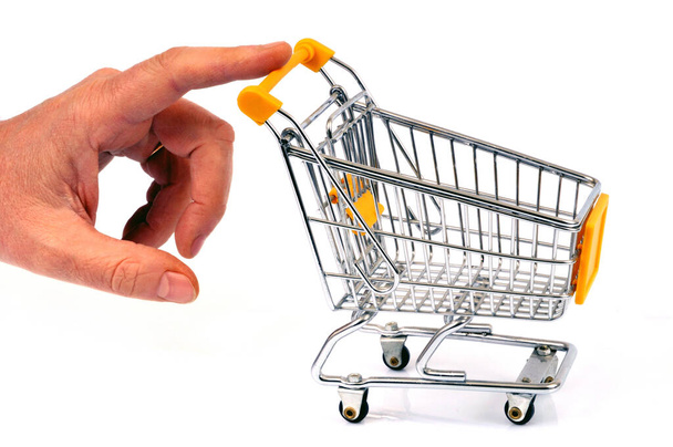 Ein Supermarkt-Einkaufswagen mit einem Finger aus nächster Nähe auf weißem Hintergrund schieben - Foto, Bild