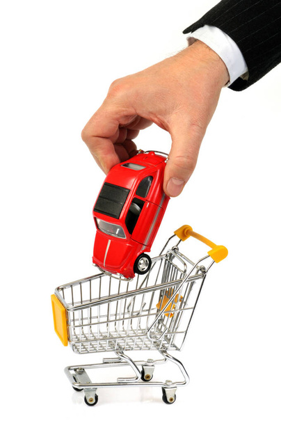 Βάζοντας ένα αυτοκίνητο σε ένα καλάθι σούπερ μάρκετ σε λευκό φόντο - Φωτογραφία, εικόνα