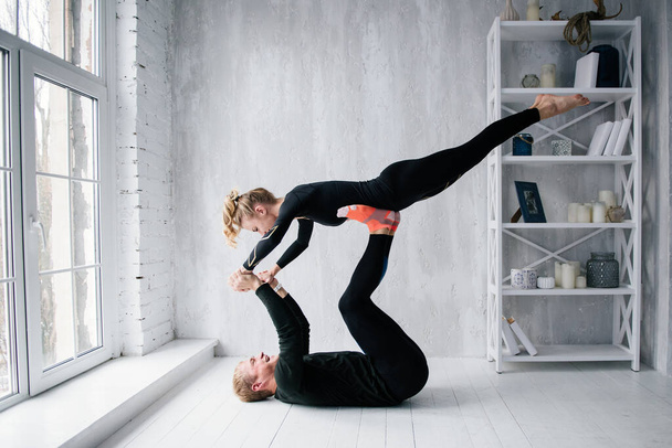 The guy and the girl in tracksuit. Black sports uniform. Male and female athletes. Pumped up body. Triathlon. Morning work-out. Set of exercises for body. Classes in pair. Workout together at home. - Foto, Bild
