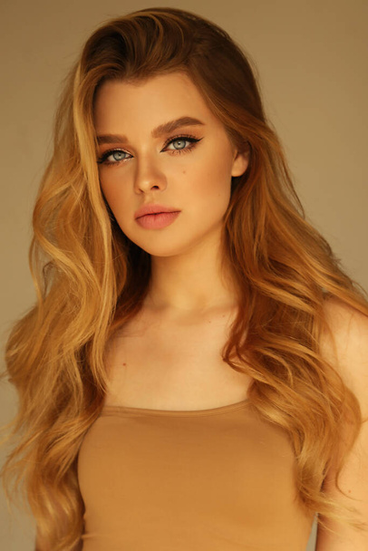fashion photo of beautiful young woman with blond natural hair and light makeup posing at studio - Fotó, kép