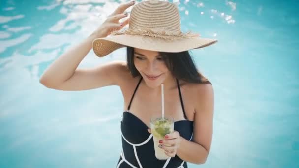 Woman in hat relaxing at pool with cosmopolitan cocktail - Πλάνα, βίντεο