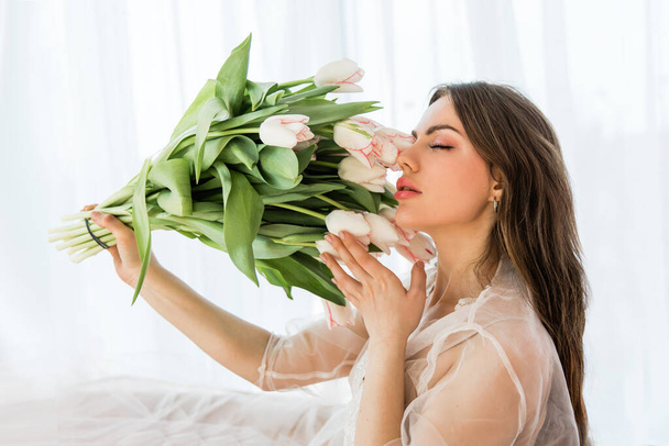 Fashion photo of beautiful lady with flowers. Home interior. Morning - 写真・画像