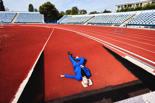 Ледачий чоловік спить втомлений лежить на трасі на стадіоні
. - Фото, зображення