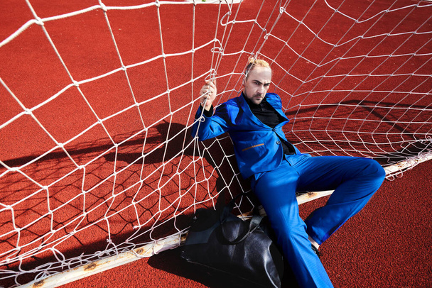 Business and quarantine. Man sitting in football gate on the track in the stadium. - Valokuva, kuva
