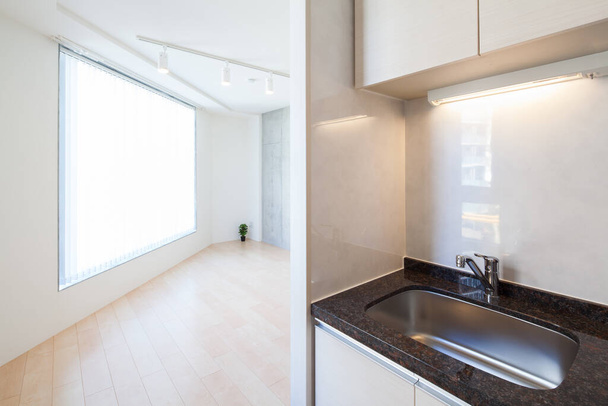 A bright and clean kitchen in a white-toned apartment room - 写真・画像