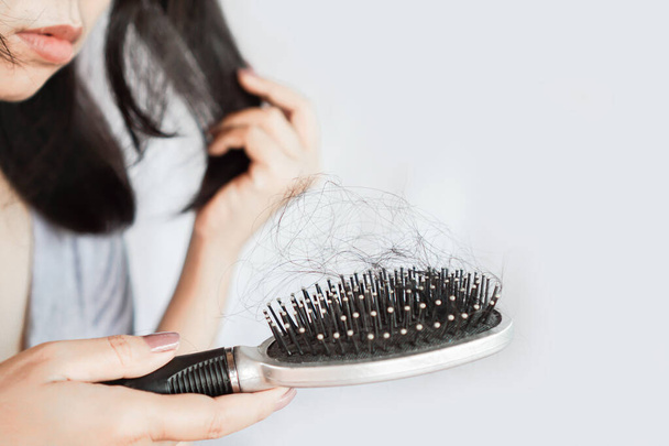 Mujer asiática cepillarse el pelo teniendo problemas con la caída del cabello en el peine
 - Foto, Imagen