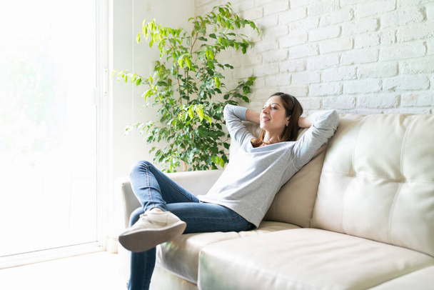 Krásná žena oblečená ležérní a užívat si svého času doma a relaxaci ve svém gauči - Fotografie, Obrázek