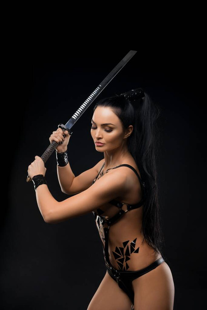 Sensual female warrior in underwear swinging sword - Fotoğraf, Görsel