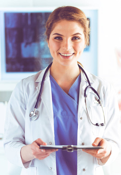 Woman doctor standing with folder at hospital - Fotoğraf, Görsel