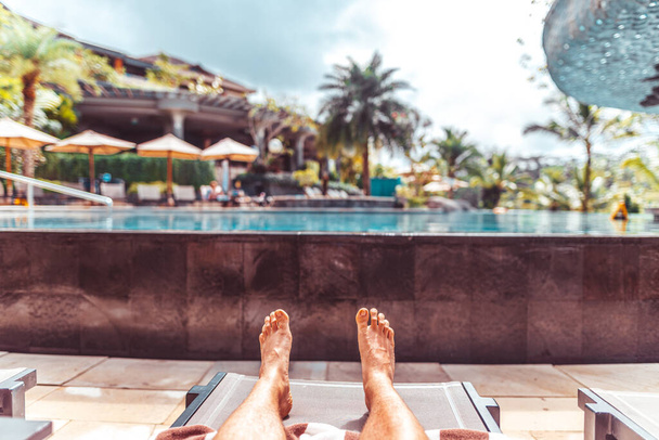 Mann liegt am tropischen Pool eines Luxus-Resorts - Foto, Bild