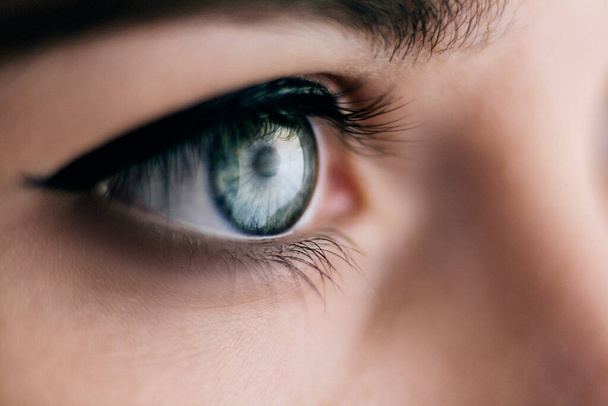 Primer plano de ojo de mujer azul con hermoso maquillaje natural. Chica mirando a un lado, belleza del cuerpo humano
 - Foto, imagen