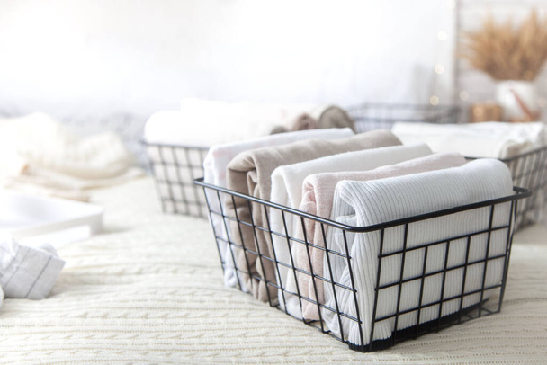 Close-up of white clothes and linen neatly folded in mesh metal containers in bedroom on background of blurred bed. Concept of the perfect organization. Advertising space - Фото, изображение