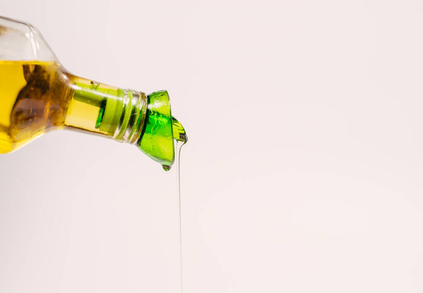 Olive oil. A stream of olive oil pours from a glass bottle. - 写真・画像